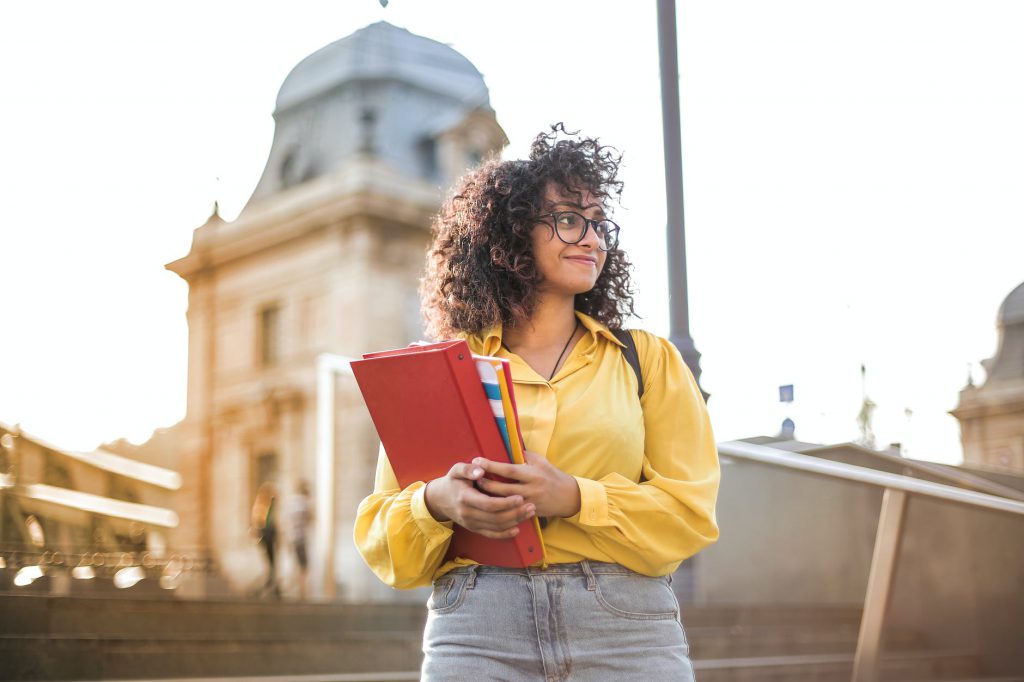 woman in yellow jacket holding red book