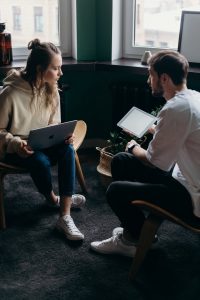 photo of couple talking while holding laptop and ipad