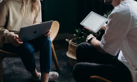 photo of couple talking while holding laptop and ipad