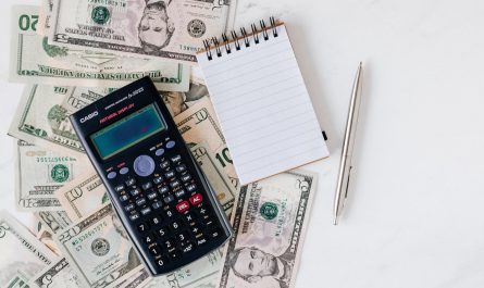 calculator and notepad placed over stack of usa dollars