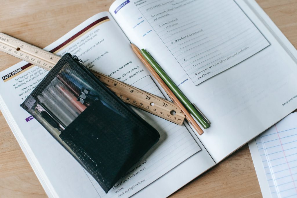 textbook with pens and ruler on table