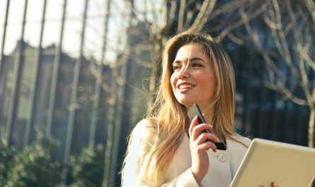 woman wearing white top holding smartphone and tablet